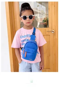Toddler blue nylon crossbody chest bag with orange fashion zipper strap shown on a child