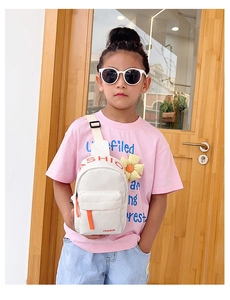 Detail of kids beige nylon crossbody bag featuring red Fashion text and orange zipper pull