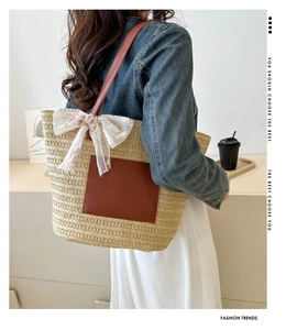 Detail of woven straw tote bag with brown leather pocket and white lace bow accessory
