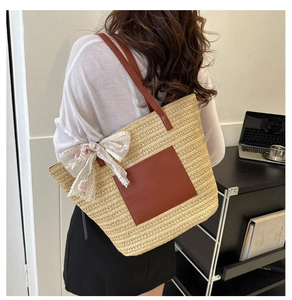 Detail of woven straw tote bag featuring brown leather pocket and lace flower bow