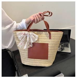 Detail of woven straw tote bag with brown leather handles and floral lace bow decoration