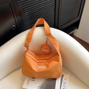 Detail der leuchtend orangefarbenen Nylon-Umhängetasche mit Mini-Geldbörse und Logo