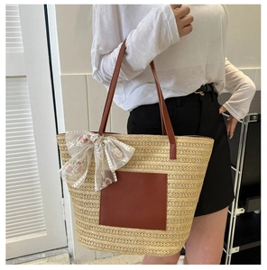 Detail of woven straw tote bag with brown PU straps and floral lace bow decoration