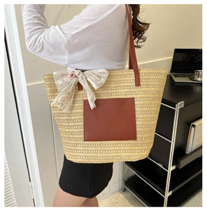 Detail of woven straw tote bag with brown leather patch and floral lace bow decoration
