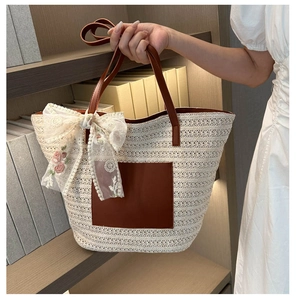 Detail of woven tote bag with brown leather pocket and floral lace bow accent