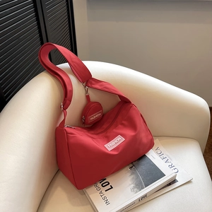 Detail der roten Nylon-Tasche mit Mini-Beutel auf Ledersofa mit einer Zeitschrift