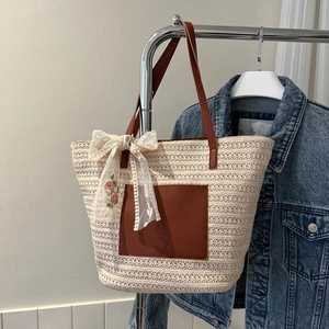 Detail of beige woven tote bag featuring brown leather pocket and floral lace bow charm