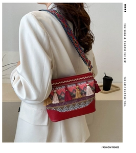 Detailed shot of ethnic red woven shoulder bag with colorful tassels and geometric strap