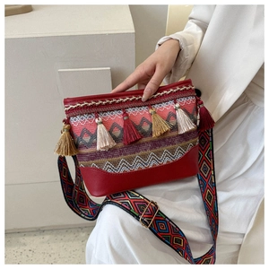 Close-up of bohemian crossbody bag with colorful tassels and ethnic woven strap