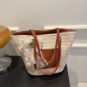 Beige woven straw tote bag with brown leather accents and floral lace ribbon detail