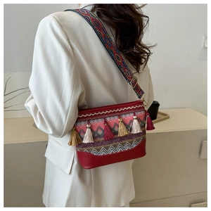 Close-up of ethnic crossbody bag featuring colorful tassels and woven geometric strap