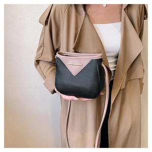 Detail of pink and black contrast crossbody bag with lychee texture and gold metal accents