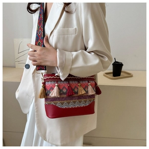 Close-up of bohemian crossbody bag with colorful fringe tassels and woven shoulder strap