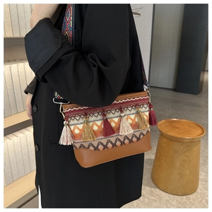 Detail of colorful bohemian crossbody bag with vibrant tassels and woven geometric strap
