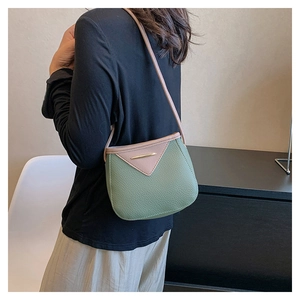 Side view of trendy green and pink leather bucket bag with metallic gold bar detail