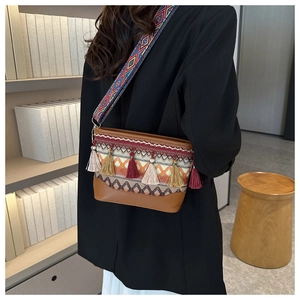 Detail of bohemian crossbody bag featuring colorful tassels and wide geometric strap