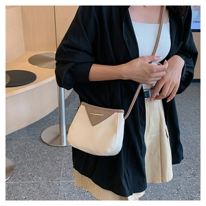 Detail of cream leather crossbody bag with brown triangular flap and gold metal fastener