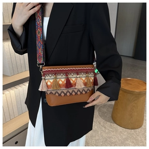 Detailed close-up of a bohemian crossbody bag featuring colorful tassels and embroidered strap