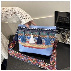 Detail of bohemian crossbody bag with colorful woven patterns and tassel charms