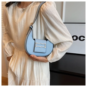 Detail of light blue semi-circle shoulder bag with silver buckle worn by a model