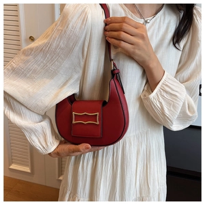 Detail of dark red crescent shoulder bag with golden buckle on a white dress