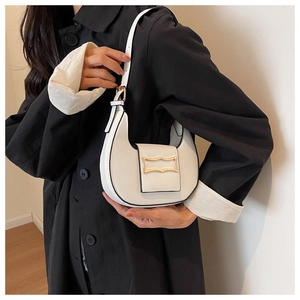 Detail of white crescent underarm bag featuring a gold buckle on black coat background