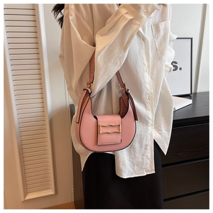 Detailed shot of pink crescent underarm bag with gold buckle on a stylish model