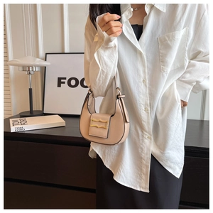 Detail of a chic cream leather hobo bag with a gold metal buckle shown on a model