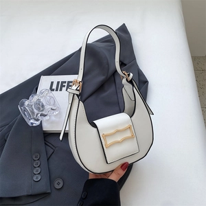 Close-up of white crescent shoulder bag with golden geometric clasp on grey blazer