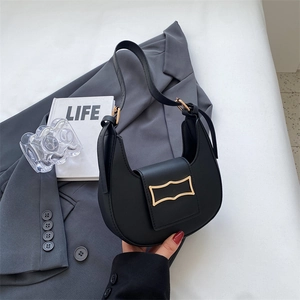 Detail of black half-moon bag with gold metal buckle on grey suit background