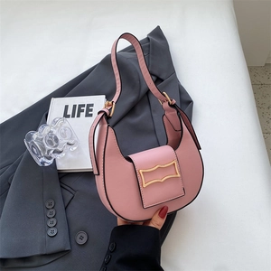 Detail of pink half-moon shoulder bag featuring a unique wavy gold metal buckle closure