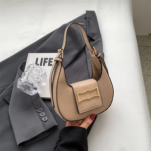 Detail of hobo bag featuring a gold geometric clasp and adjustable beige strap