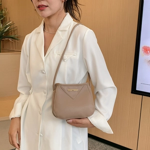 Chic khaki pebbled leather bucket bag with gold hardware worn by model in white suit