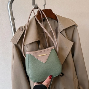 Chic green and purple lychee texture bucket bag with gold buckle on a stylish trench coat
