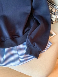 Dunkelblauer Lagenlook-Sweatshirt mit gestreiftem Saumdetail auf weichem Hintergrund
