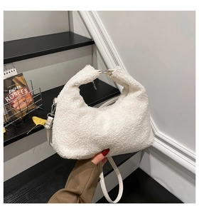 Detail of white faux shearling crescent shoulder bag featuring silver magnetic closure
