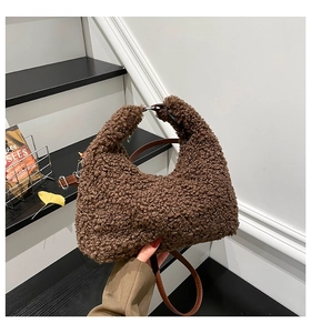 Close-up of brown teddy fur crescent shoulder bag with a slim leather strap in hand