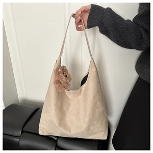 Detail of beige suede shoulder bag featuring a cute brown plush bear charm and strap