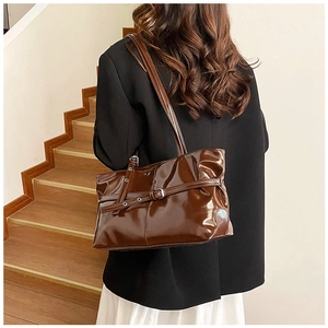 Sac fourre-tout en cuir marron brillant avec boucle argentée porté à l'épaule