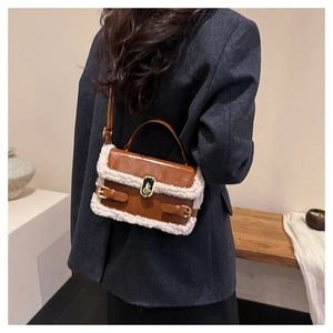 Detail of a brown leather handbag with plush shearling trim and golden twist lock