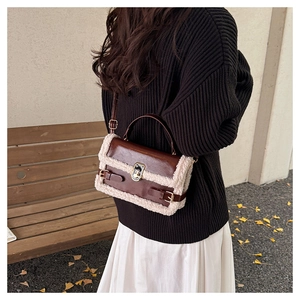 Brown faux leather crossbody bag with white shearling trim on park bench with leaves