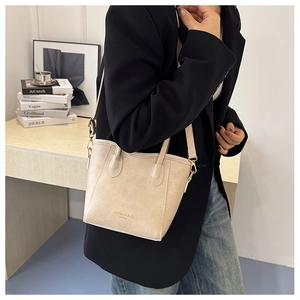 Close-up of beige bucket bag texture with gold Fashion & BaG lettering and slim handle
