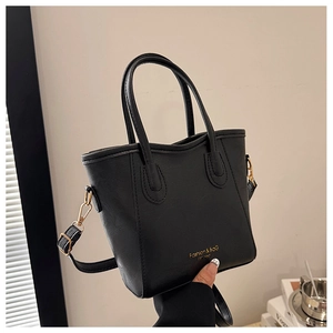Close-up of black bucket bag featuring litchi texture and gold metal hardware