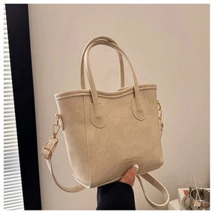 Close-up of beige bucket bag showing litchi grain texture and gold metal hardware