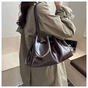Détail d'un sac cabas en cuir verni marron foncé avec plis élégants et souples