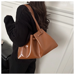 Gros plan d'un sac cabas marron ambre brillant porté à l'épaule pour un look d'hiver