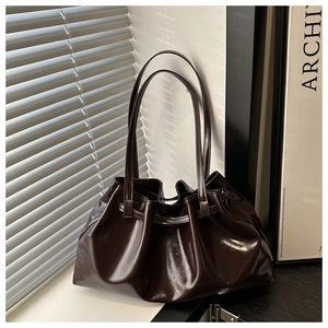 Détails de la texture en cuir ciré marron foncé et design plissé sur le sac fourre-tout