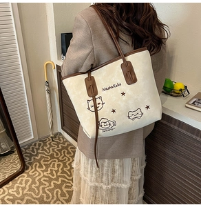 Detail van de grote beige shopper met kattenprint en bruine lederen riemen bij model