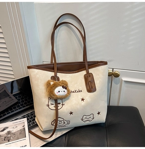 Detail van de beige shopper met kattenillustratie en een bruine pluche tashanger