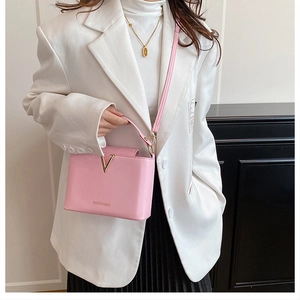 Close-up of pink leather handbag with gold V decoration and fashion logo text detail
